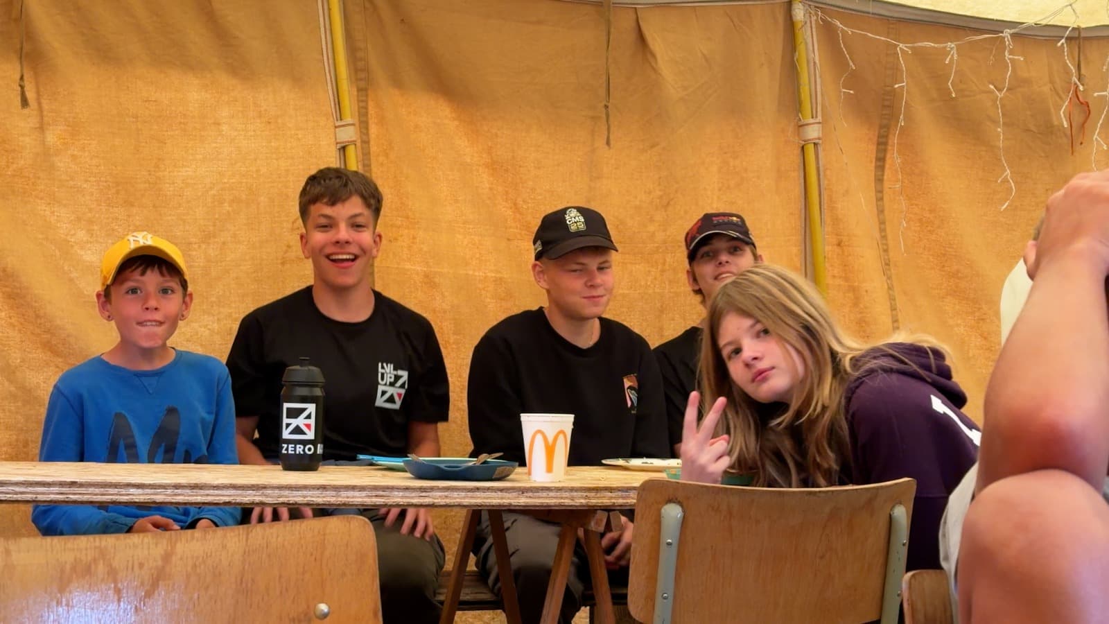 Deelnemers van het ZERO zomerkamp zitten samen aan tafel in een tent